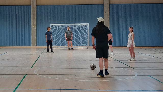People playing futsal at a sports hall.